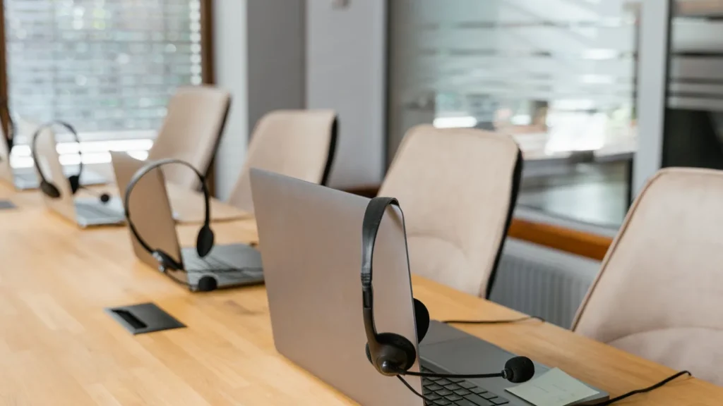 Laptops and headsets set up around a meeting table for a cloud phone system