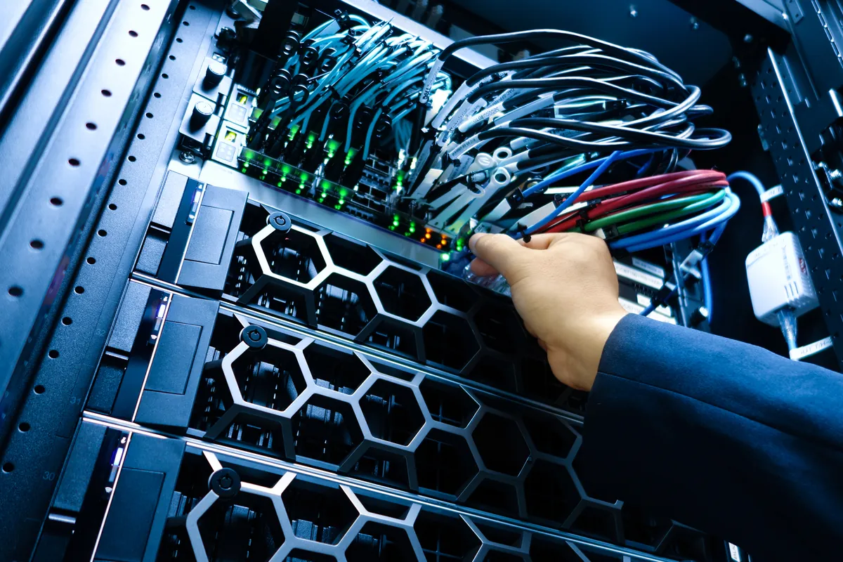 IT technician connecting network cables in a server rack, for wholesale SIP trunks and white label hosted PBX